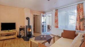 Een woonkamer met een televisie, een open haard, een bank en een raam met gordijnen.