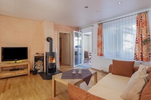 Ein Wohnzimmer mit Fernseher, Kamin, Sofa und einem fenster mit Vorhängen.