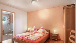Een slaapkamer met een houten bed, een nachtkastje, een stoel en een kledingkast.