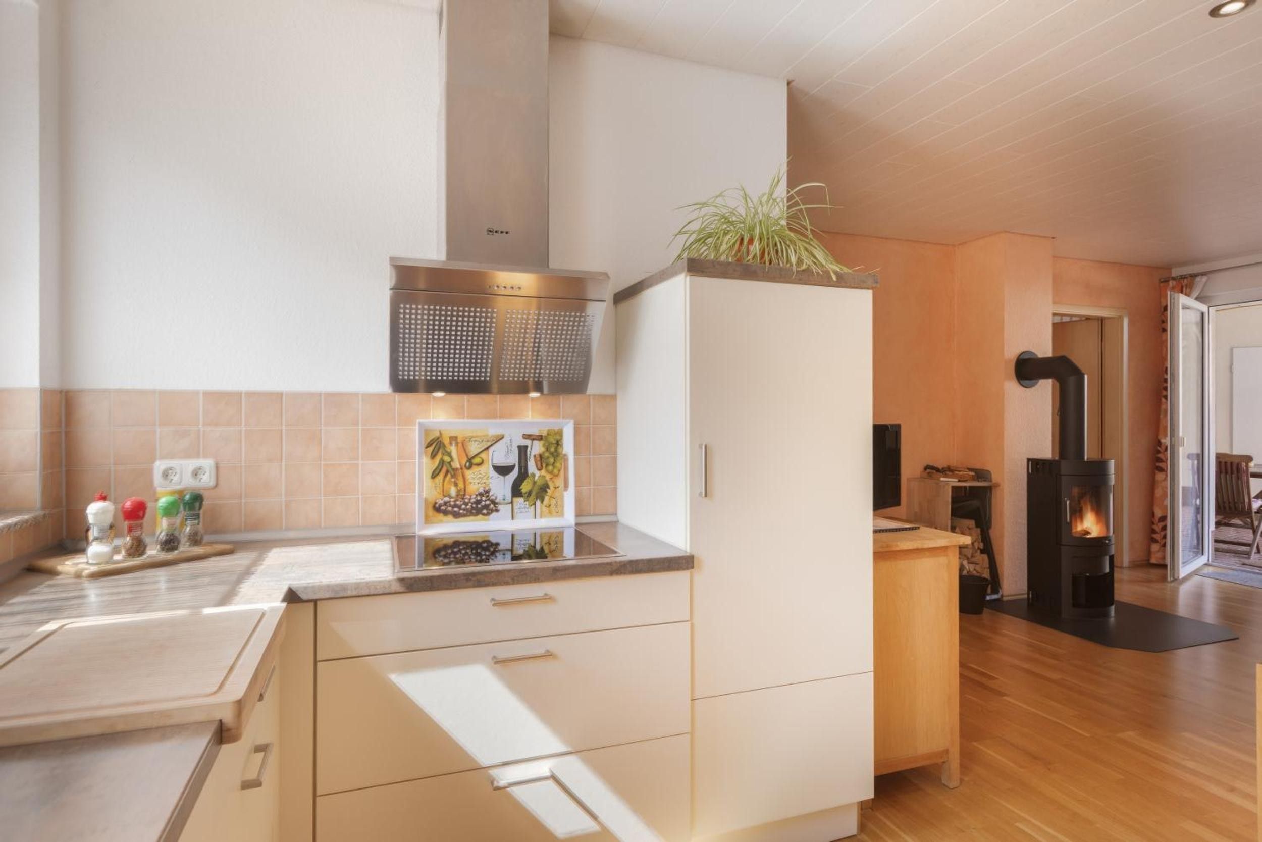 Una cucina moderna con piano cottura integrato, mobili in legno e zoccolo rivestito in piastrelle.
