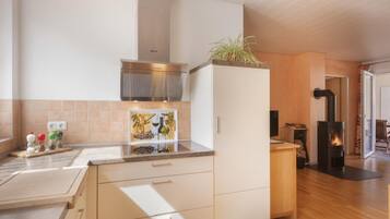 Una cucina moderna con piano cottura integrato, mobili in legno e zoccolo rivestito in piastrelle.