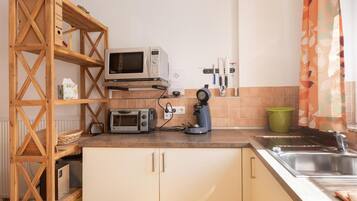Eine Küche mit einer Holzregaleinheit, einer Mikrowelle, einem Toaster und einem Wasserkocher.