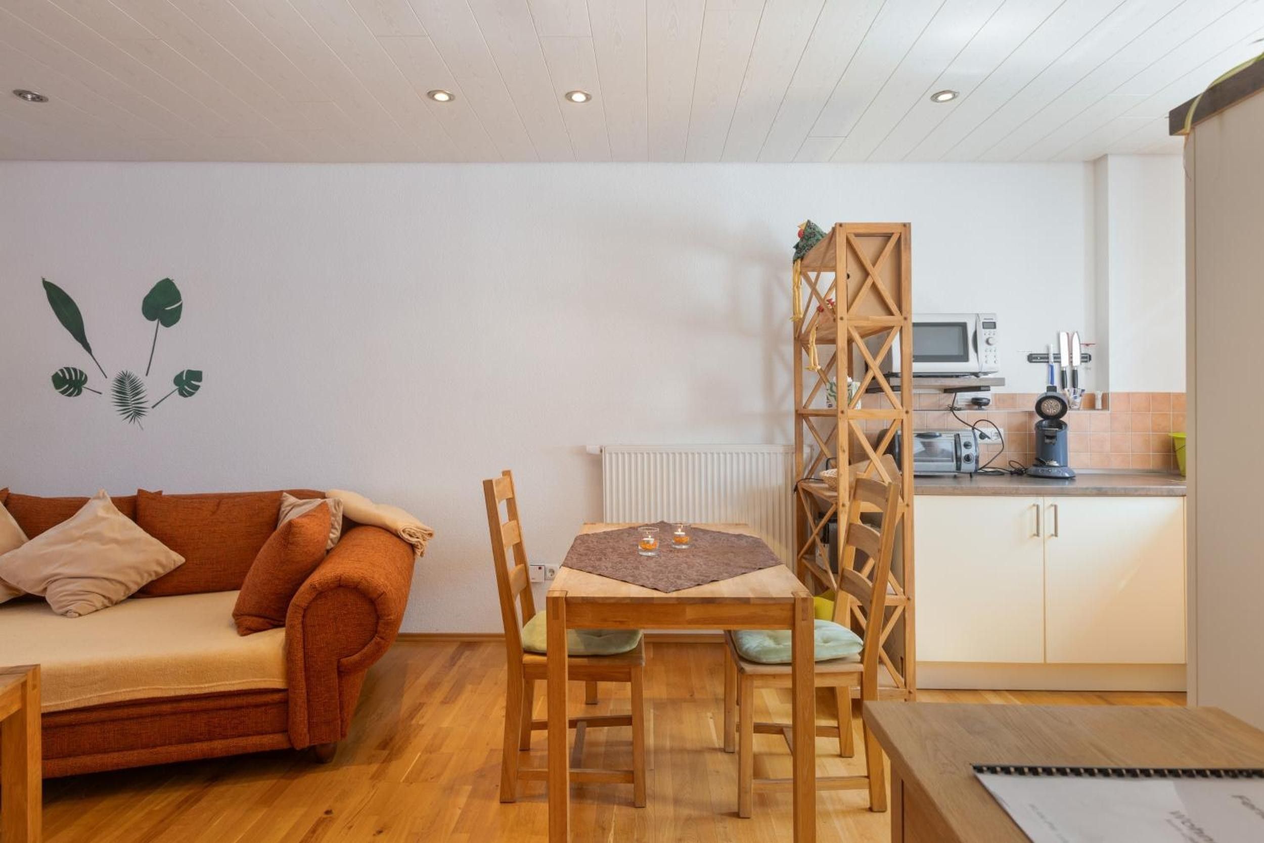 A cozy living area with a sofa, a dining table, and chairs. There's a kitchen area with a microwave and toaster.