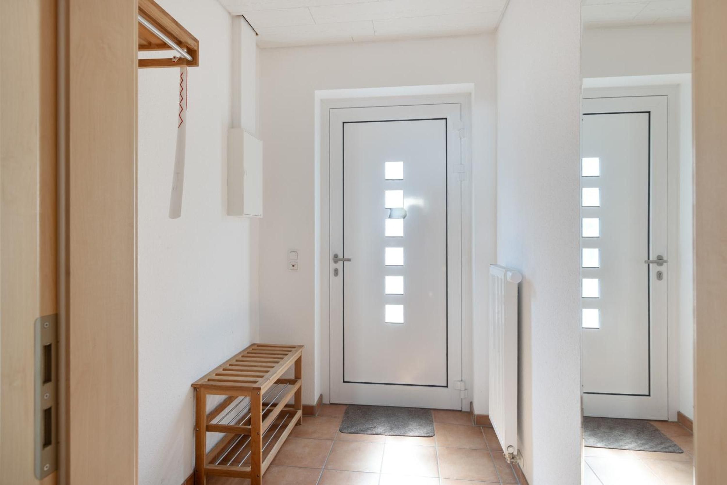 Un passadís amb dues portes blanques, una banca de fusta i un radiador.