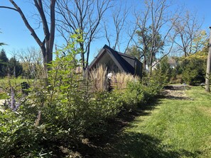 A house with a sloped roof, surrounded by a garden with various plants and trees.