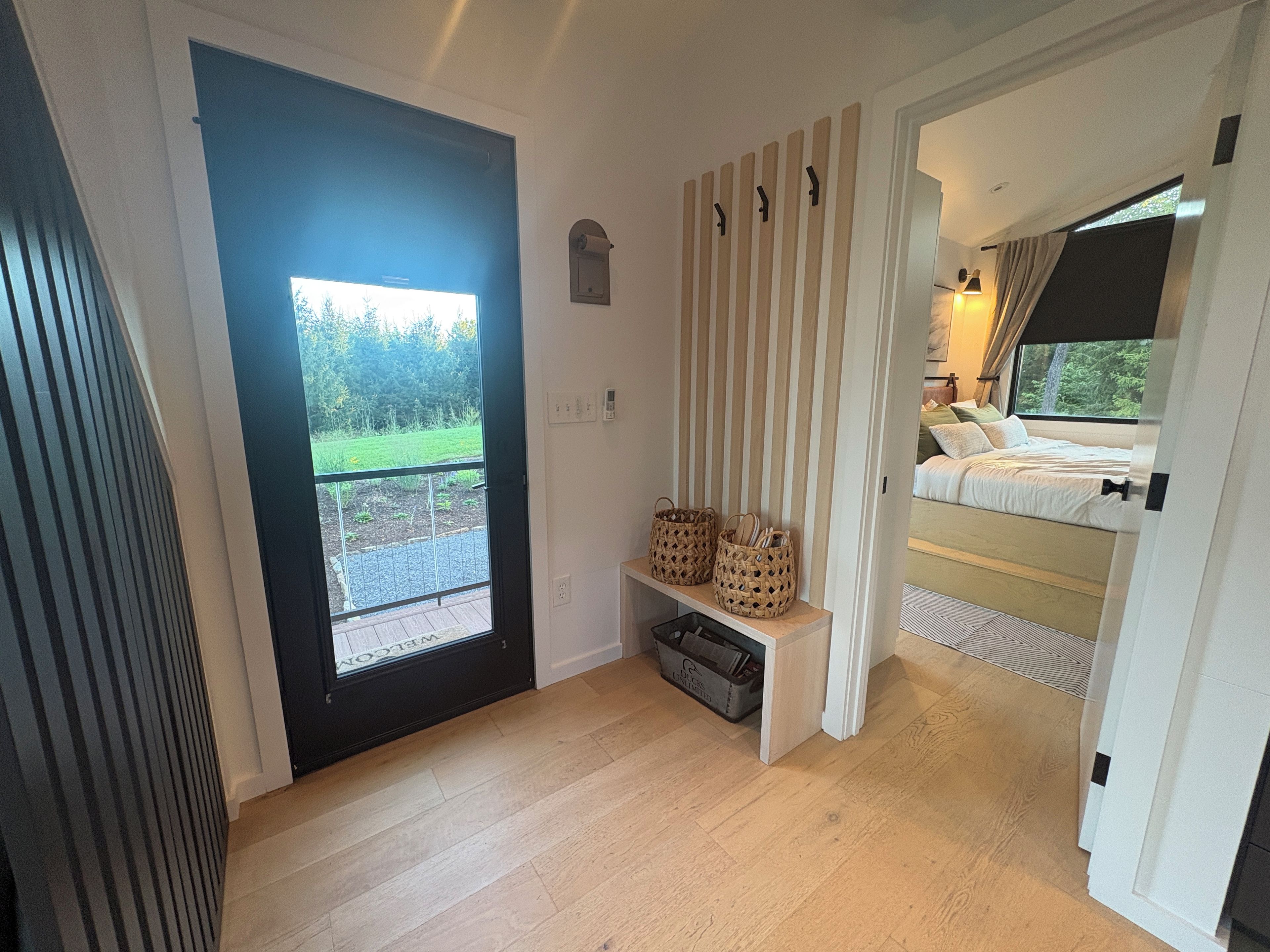 A bedroom with a bed, a bedside table, a window, and a door leading to a balcony.