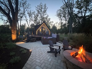 A cozy outdoor patio with a hot tub, seating, and a fire pit.