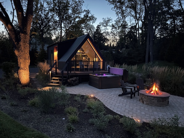 A modern outdoor living space with a hot tub, seating area, and a fire pit.