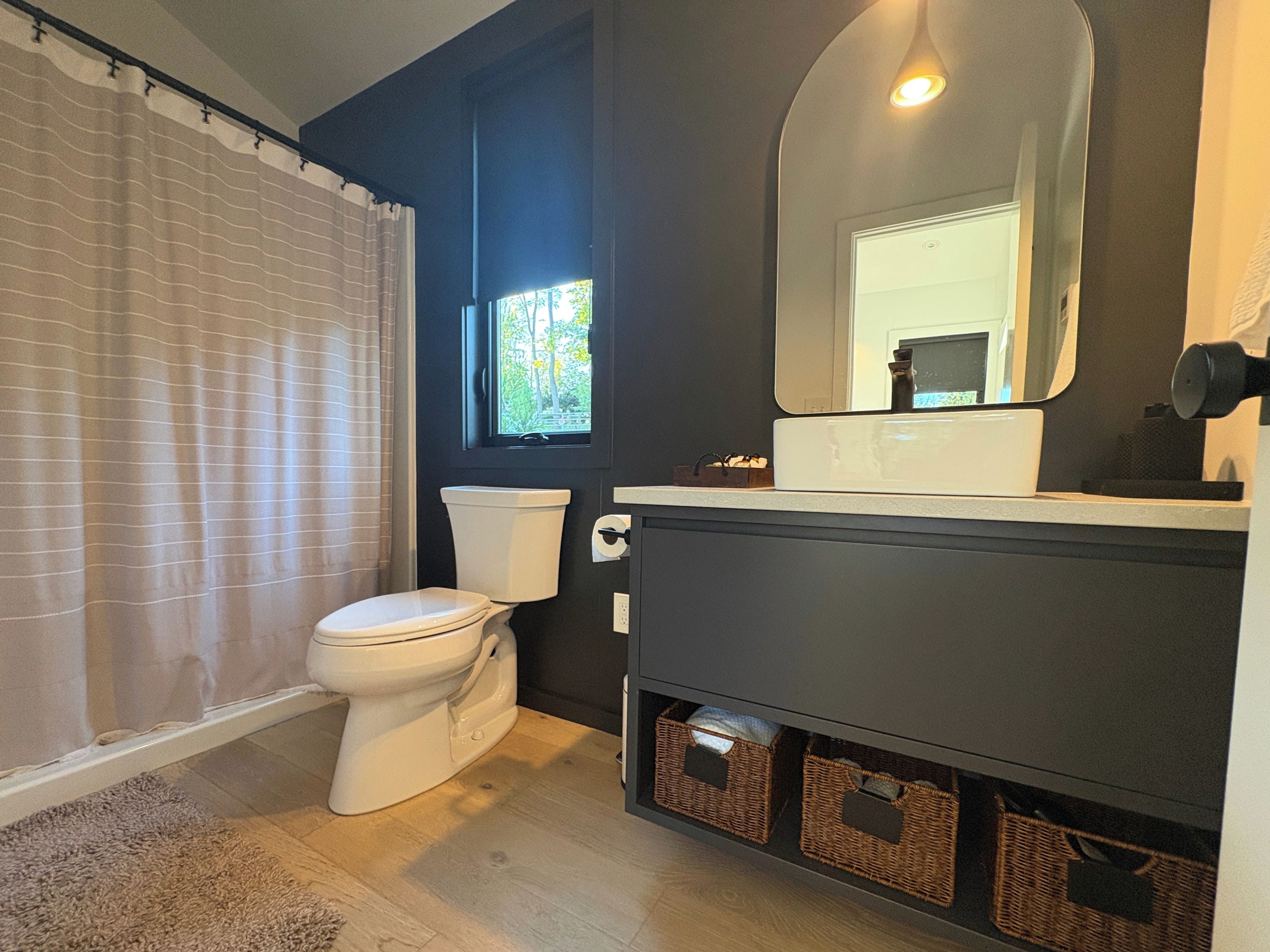 Une salle de bain avec des toilettes, un lavabo, un miroir et une fenêtre.