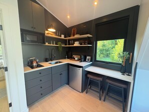 A compact kitchen with a built-in microwave, a sink, and a window providing a view of greenery outside.