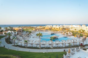 Un resort con piscina central, tumbonas y vista al mar.
