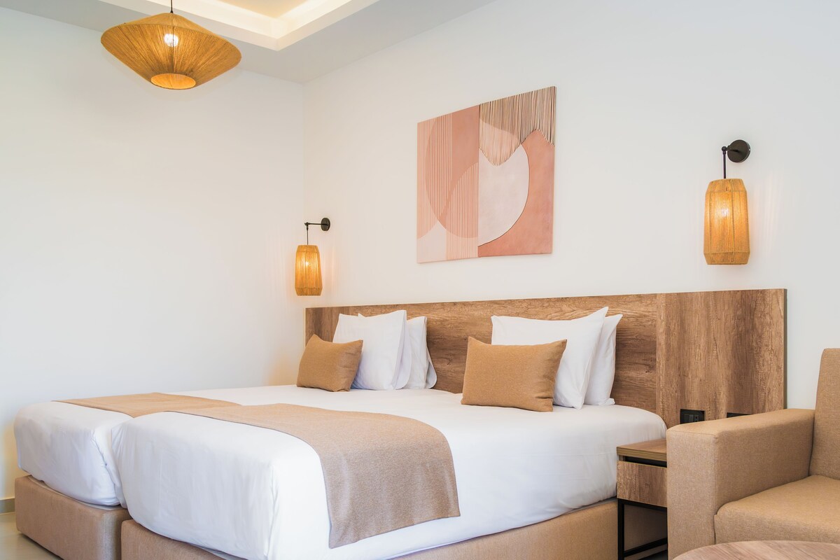 Une chambre d’hôtel avec un grand lit, deux tables de chevet, une chaise et une œuvre d’art accrochée au mur.