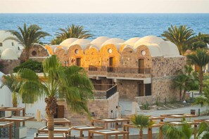 Un edificio costero con varias estructuras abovedadas, un balcón y vista al mar.