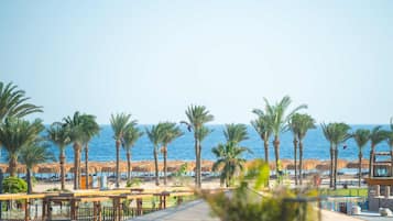 A resort with a pool area, palm trees, and a view of the ocean.