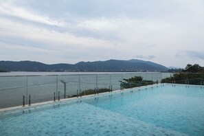 A swimming pool with a view of a body of water and mountains in the distance. - Duna Loft overlooking the Lagoon | Pool and gym (Florianópolis)
