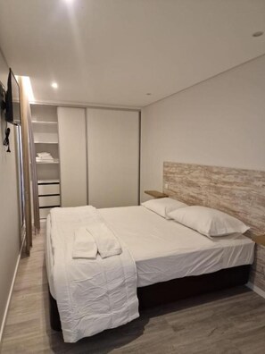 A modern bedroom with a large bed, a wardrobe, and a bedside table. - Ocean Paradise Til (Funchal)