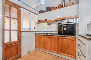 Eine Küche mit Holzschränken, einem Edelstahlkühlschrank und einer Mikrowelle.