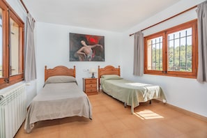 Quarto com duas camas, mesa de cabeceira, quadro e janela com cortinas.