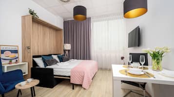 Une chambre d’hôtel moderne équipée d’un lit, d’une table de chevet, d’une chaise et d’un coin repas avec une table et des chaises.
