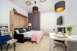 A modern hotel room with a bed, bedside table, chair, and a dining area with table and chairs. - Sun&Snow Aleje Jerozolimskie   (Warszawa)