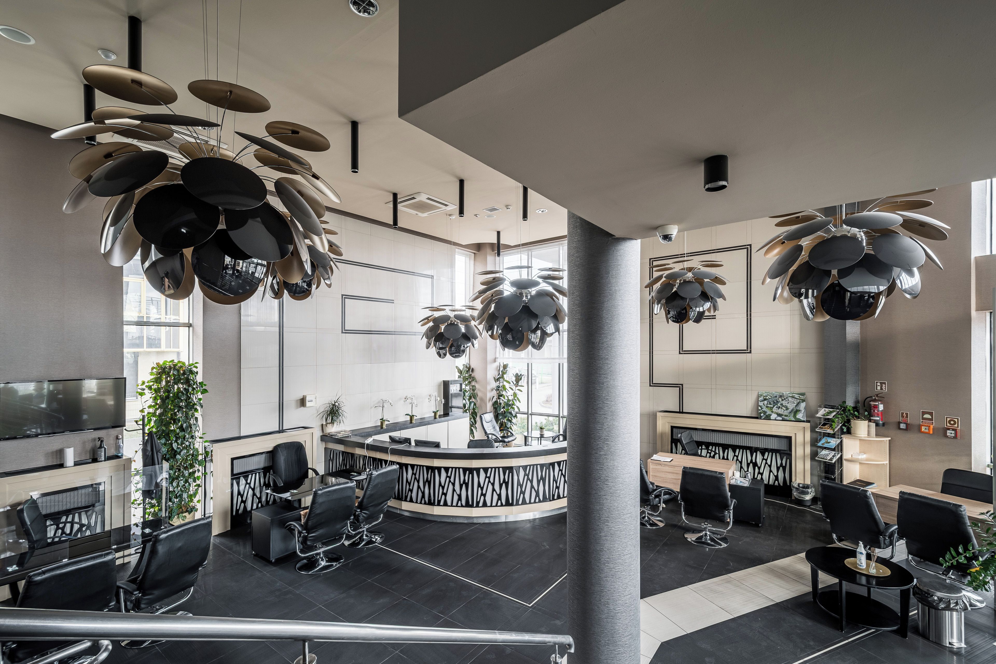 A modern interior with a reception desk, seating area, and unique ceiling fixtures.