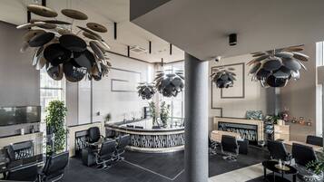 A modern interior with a reception desk, seating area, and unique ceiling fixtures.