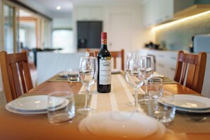 A dining table set with plates, glasses, and a bottle of wine. - Oakdean Coastal Escape | Pet Friendly (Ocean Grove)