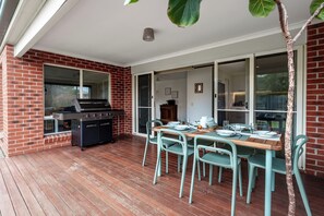 An outdoor patio with a grill, dining table, and chairs. - Oakdean Coastal Escape | Pet Friendly (Ocean Grove)