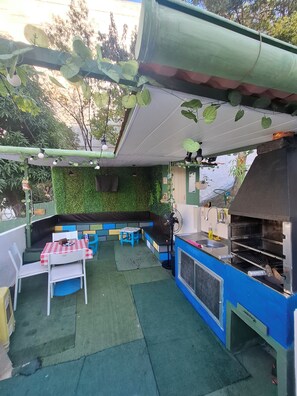 Een terras met een grillplaats, een tafel met geruit tafelkleed en een bank.