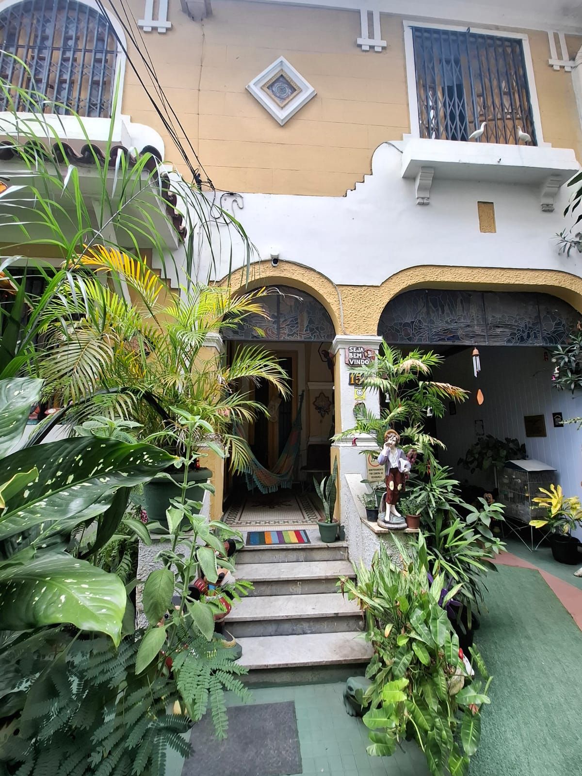 A building with a central entrance, surrounded by lush greenery and a variety of plants.