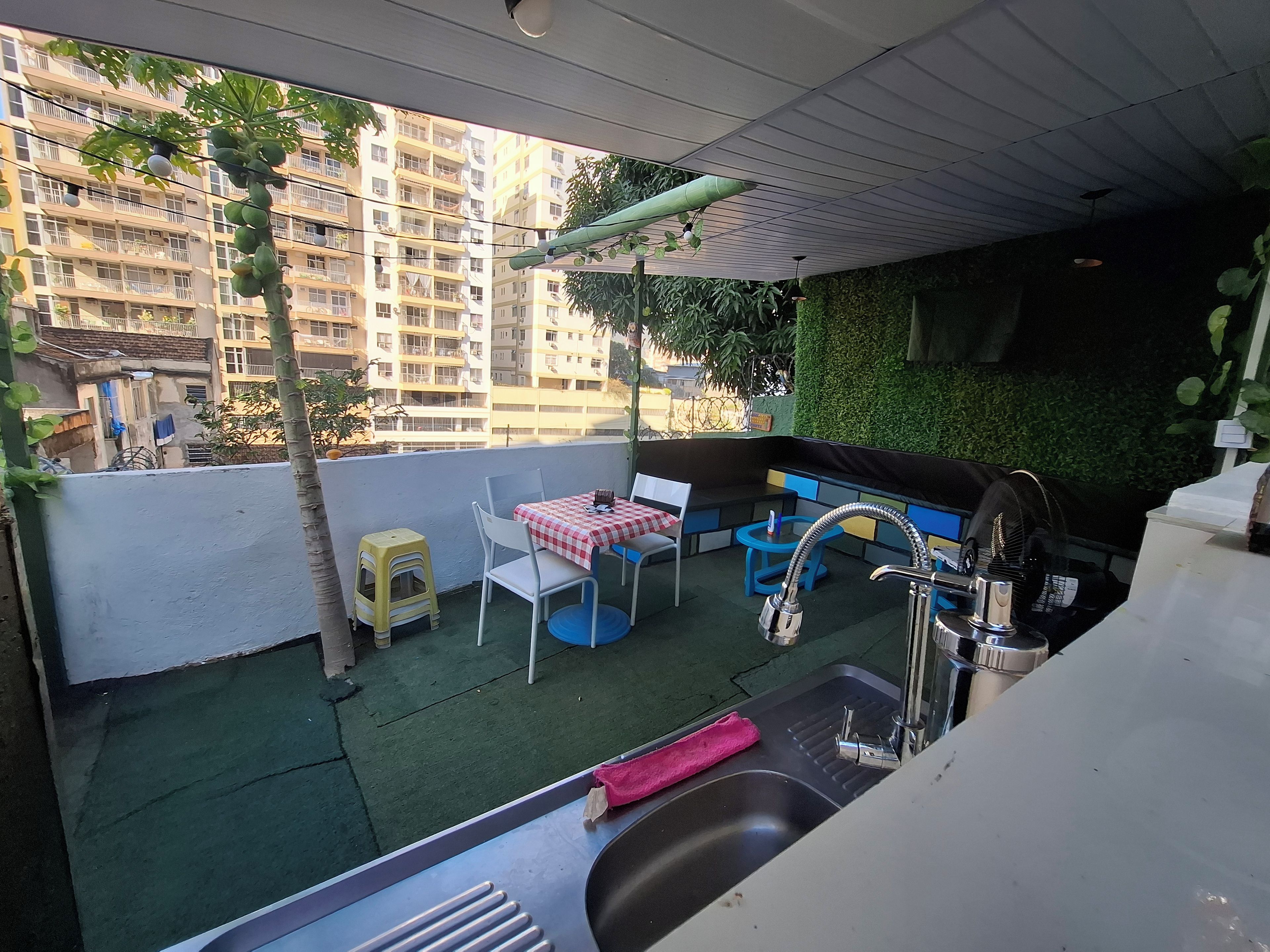 Eine Dachterrasse mit Sitzgelegenheit, Spüle und Blick auf ein Wohngebäude.