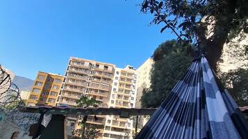 A hammock with a view of a building complex and a tree.