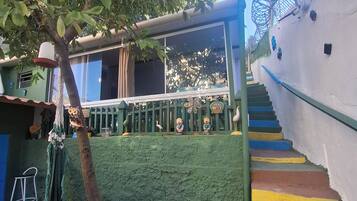 A staircase with colorful steps leading up to a green-roofed structure, surrounded by decorative statues and a tree.