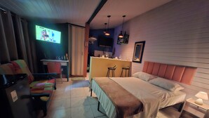 Een hotelkamer met een bed, nachtkastjes, een bureau met stoel, een televisie en een klein drankgedeelte.