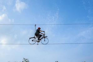 A person performing a bicycle trick between power lines. - Trance Veechika Resort (Vikarabad)