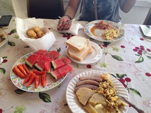 Una mesa con diferentes alimentos, incluyendo sandía, pan y un plato de huevos revueltos.