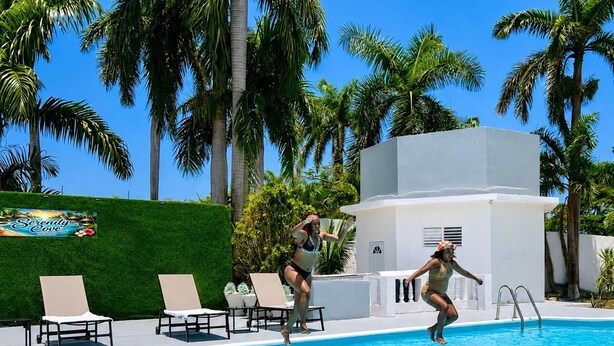 A swimming pool with lounge chairs and palm trees in the background. - Serenity Cove Resorts (St. Ann Parish)