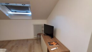 A room with a sloped ceiling, a wooden desk with a television, a radiator, and a bed. - Apartment 'Eddy Home' with Wi-Fi (Bellano)