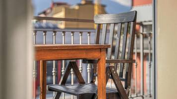 Una sedia di legno con struttura metallica, posizionata su un balcone dotato di ringhiera in metallo.