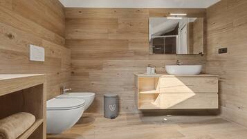 Un bagno moderno con rivestimenti in legno, un lavandino bianco, un water e un bidet.
