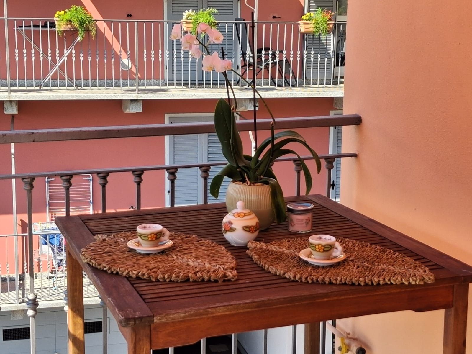 Un balcone con un tavolo, piante in vaso e una ringhiera.