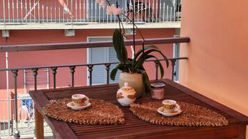 Un balcone con un tavolo, piante in vaso e una ringhiera.