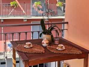 Ein Balkon mit Tisch, Topfpflanzen und Geländer.