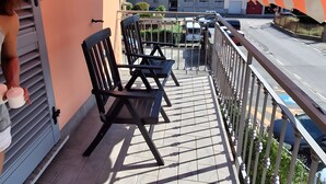 A balcony with chairs and a table, overlooking a street and buildings. - Apartment 'Eddy Home' with Wi-Fi (Bellano)