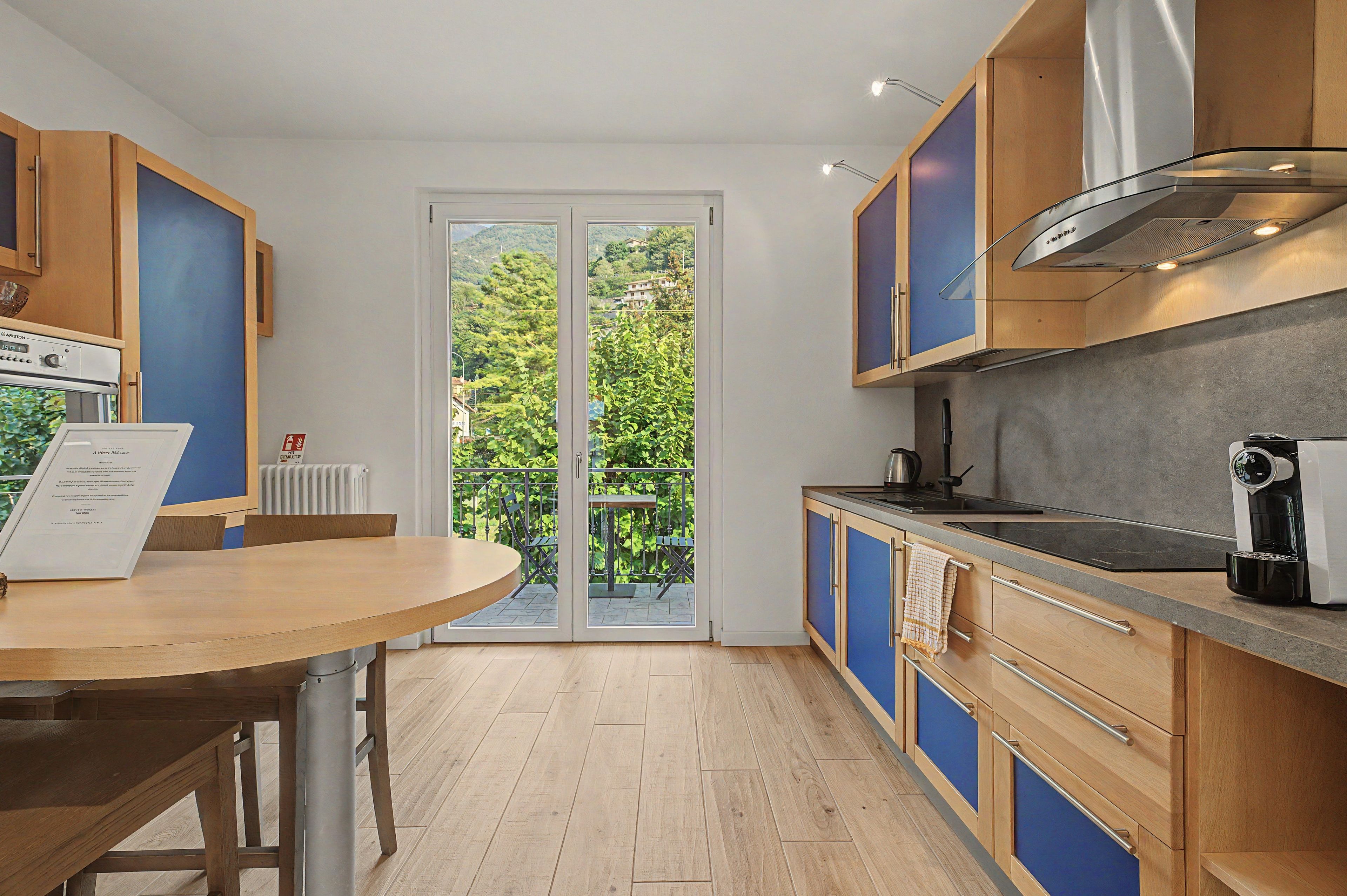 Una cocina moderna con comedor, que incluye un horno empotrado, una cafetera y vistas a través de puertas de vidrio.