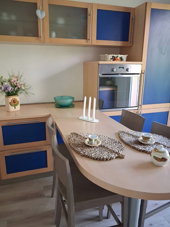 Eine moderne Küche mit eingebautem Backofen, einem Esstisch mit Platzsets und einer dekorativen Vase mit Blumen.