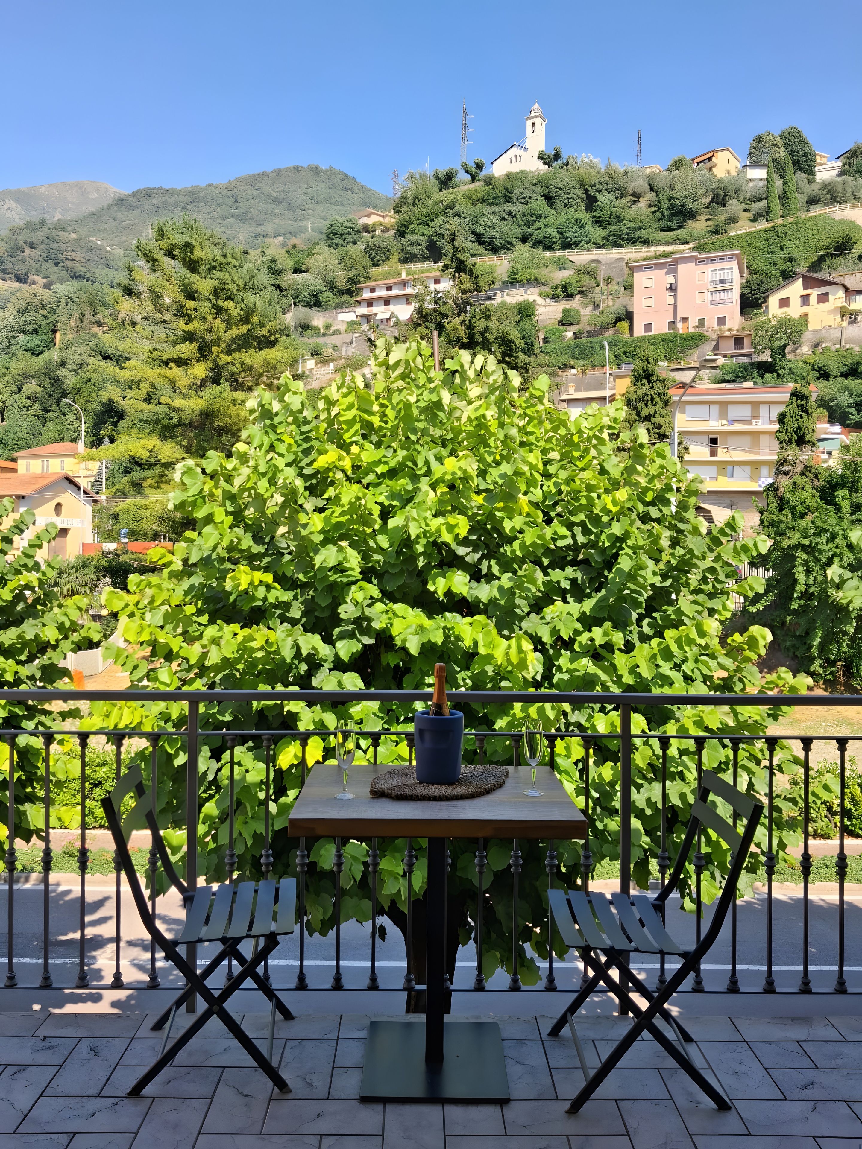Una terrazza con un tavolo, due sedie e una bottiglia di champagne.