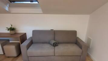 A modern living room with a grey sofa, a small side table, and a potted plant.