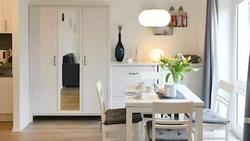 A modern dining area with a white table, chairs, and a vase of flowers.