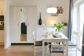 Un comedor moderno con una mesa blanca, sillas y un jarrón con flores.
